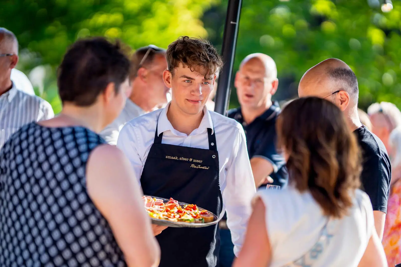 Cateraar serveert hapjes aan gasten op een buitenfeest